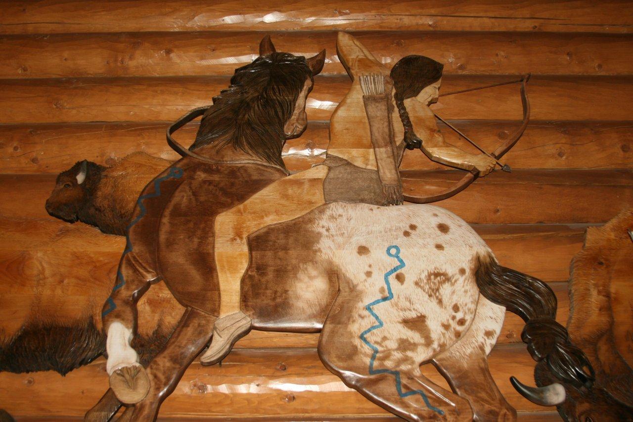 Sculpture of a Native American man riding a horse hunting bison