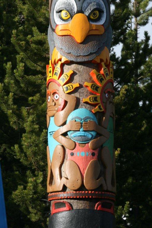 Middle segments of totem pole, including a bird-like segment and a segment depicting people