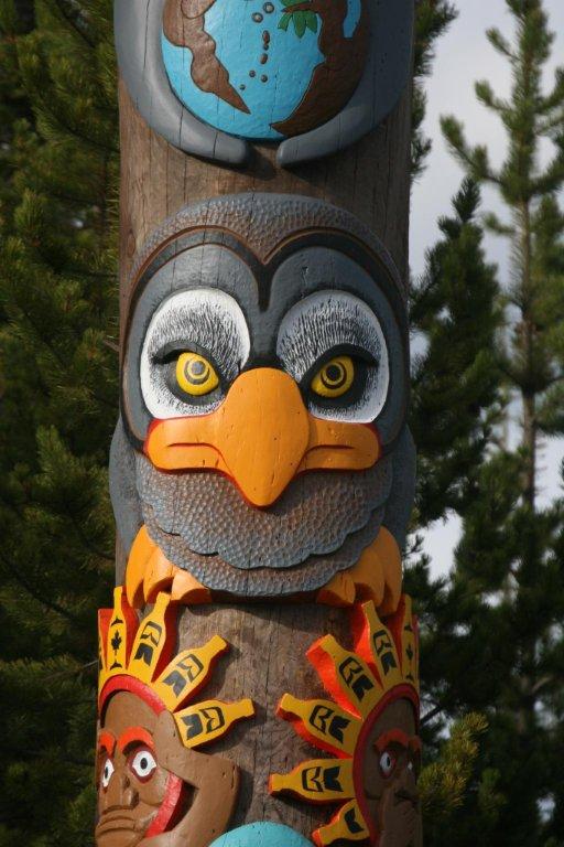 Middle segments of totem pole, including a bird-like segment and a segment depicting people